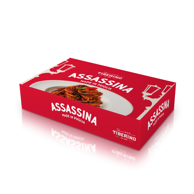 Scatola rettangolare rossa L'Assassina Gourmet BOX con logo Tiberino 1888 e immagine di spaghetti rossi su piatto bianco.