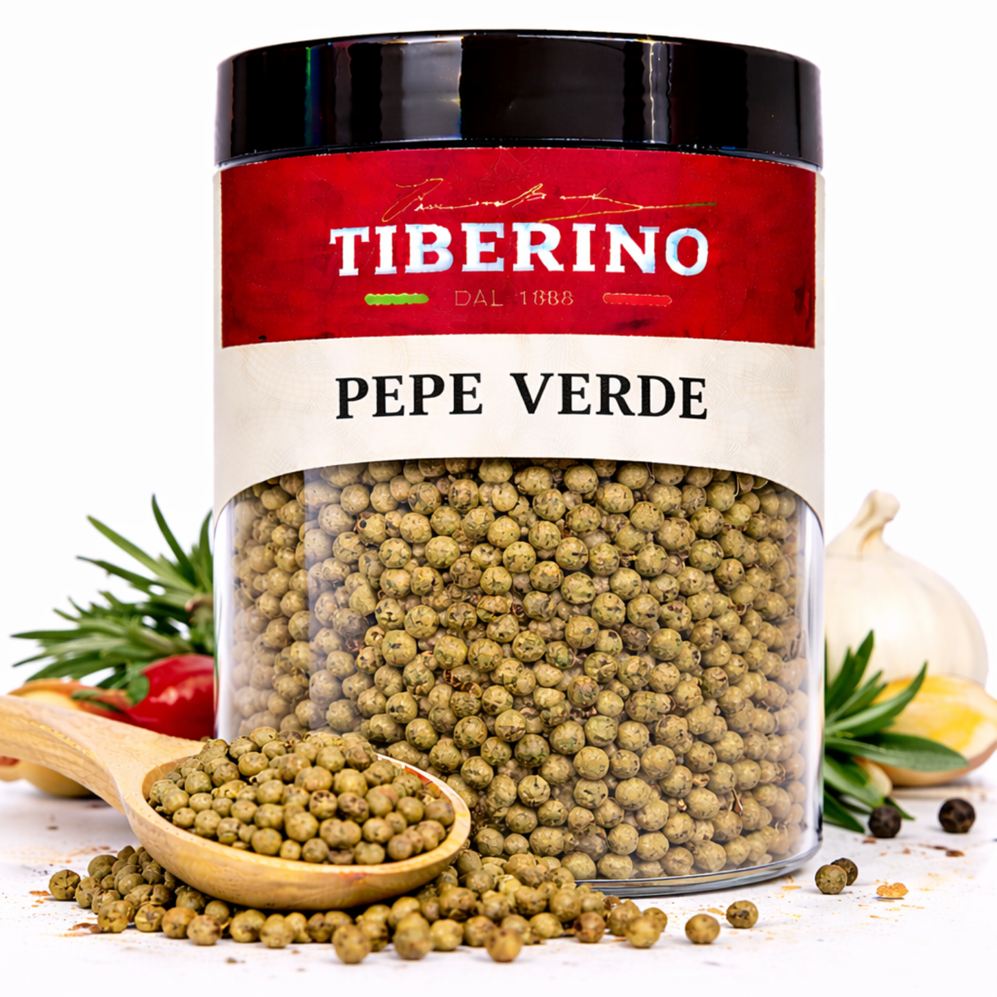 Vasetto trasparente di Pepe Verde Tiberino 1888 con tappo nero, cucchiaio di legno e spezie sparse.