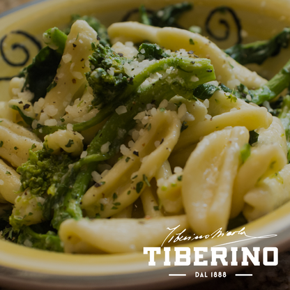 Cavatelli pugliesi con broccoli e fagioli, conditi con formaggio grattugiato ed erbe, in una ciotola gialla decorata.