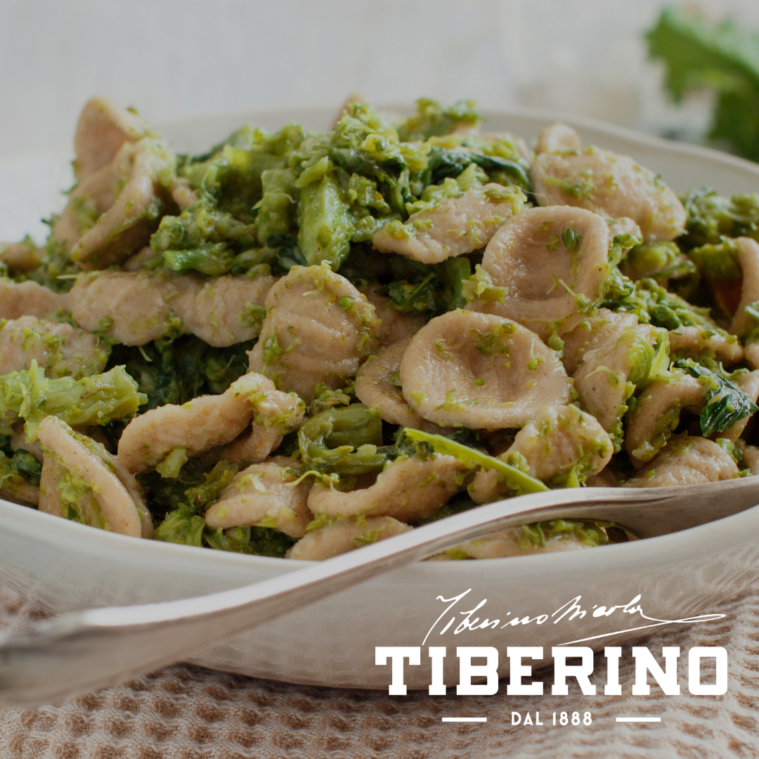 Orecchiette Baresi con broccoli e pomodoro secco in una ciotola bianca, con forchetta d'argento.