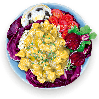 Spezzatino vegano giallo con funghi porcini e purè di patate, servito in una ciotola blu con radicchio, pomodorini, barbabietola e fungo champignon.