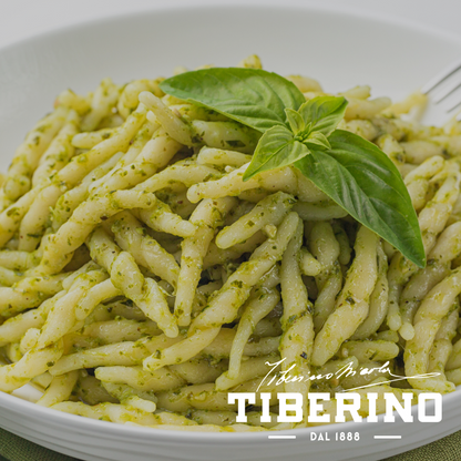 Trofiette al pesto di basilico genovese in una ciotola bianca, guarnite con una foglia di basilico fresco.