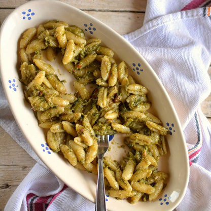 piatto di ceramica ovale con cavatelli con verdure su strofinaccio bianco su tavola di legno grezzo