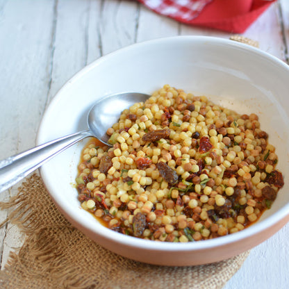 piatto di pasta fregola su tavola di legno e tovagliolo di iuta