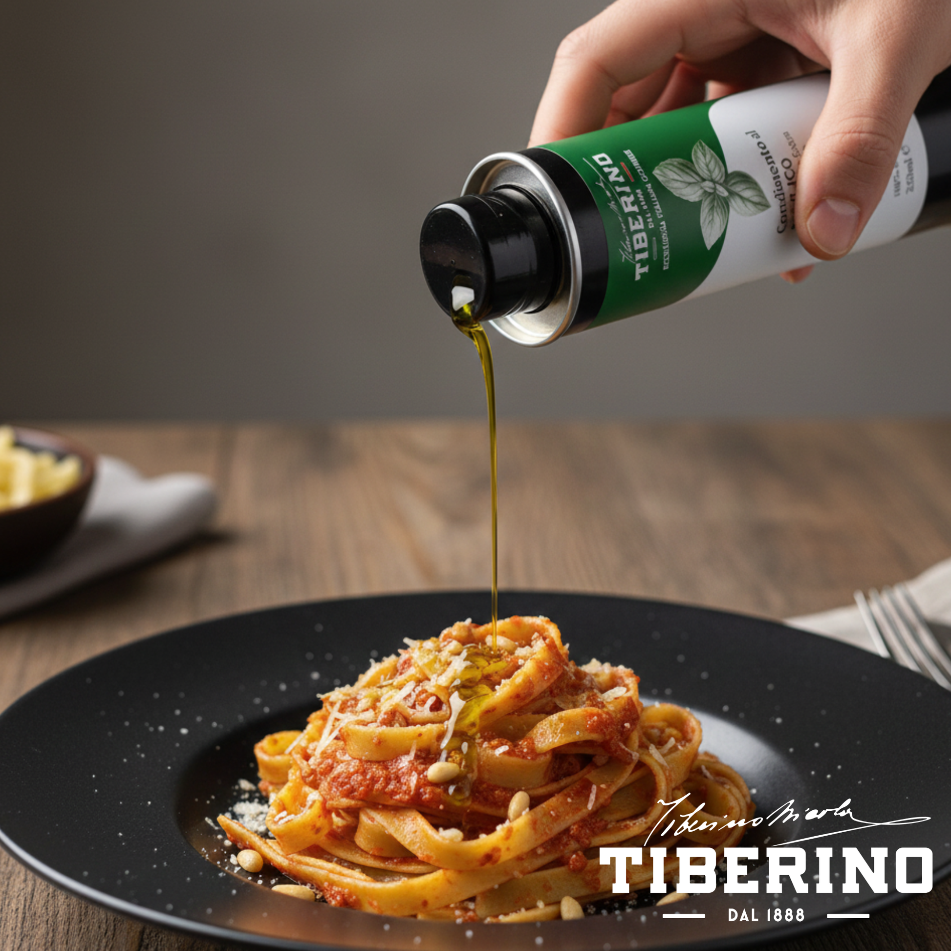 Mano versa olio extravergine di oliva al basilico Tiberino 1888 da lattina verde e bianca su tagliatelle al pomodoro con pinoli e parmigiano.