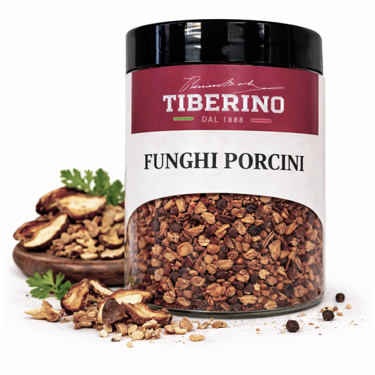 Barattolo in vetro trasparente con etichetta rossa Tiberino 1888, contenente briciole di funghi porcini essiccati marroni.