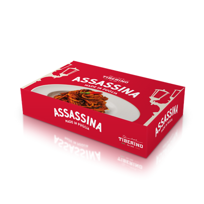 Scatola rettangolare rossa L'Assassina Gourmet BOX con logo Tiberino 1888 e immagine di spaghetti rossi su piatto bianco.