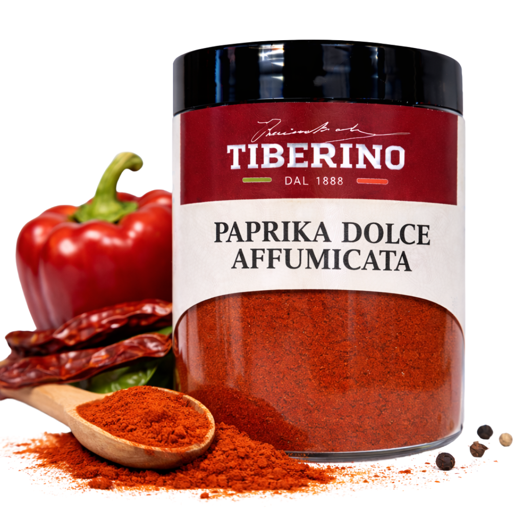 Barattolo trasparente Tiberino 1888 di paprika dolce affumicata, con cucchiaio di legno, peperone rosso e peperoncini secchi.