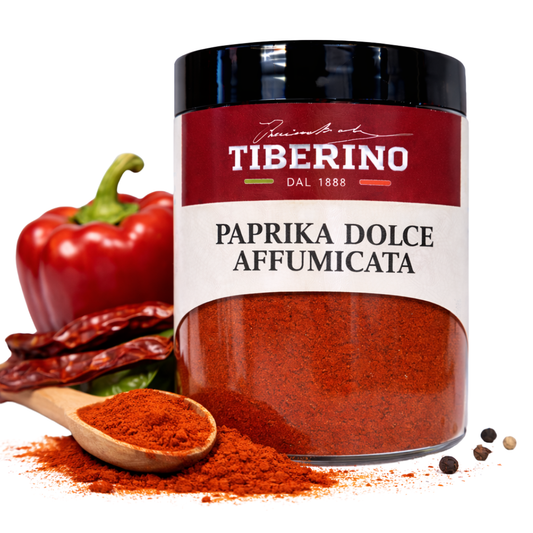 Barattolo trasparente Tiberino 1888 di paprika dolce affumicata, con cucchiaio di legno, peperone rosso e peperoncini secchi.