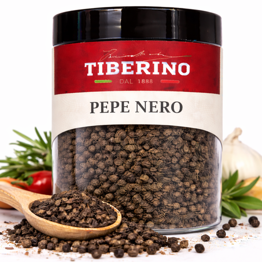 Barattolo trasparente di Pepe Nero Tiberino 1888 da 50g con etichetta rossa e beige, cucchiaio di legno con grani.