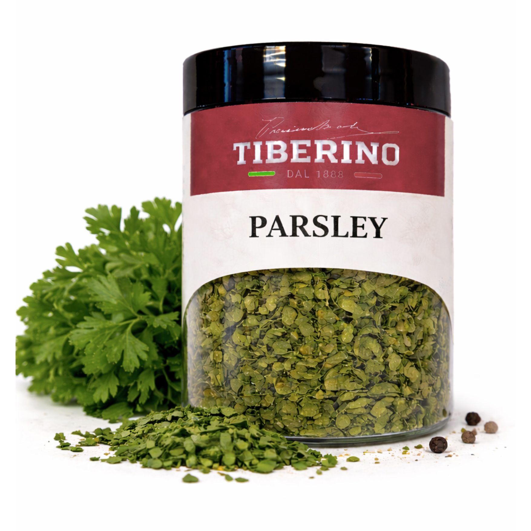 Vaso di vetro trasparente Tiberino 1888 con prezzemolo secco verde, etichetta rossa e bianca, prezzemolo fresco e grani di pepe.